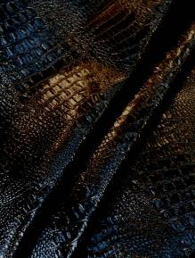 Draped curtain image of Imitation Aligator hide upholstery fabric in Vinyl Faux Gator color black, in stock at our store, available by the yard